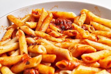 Close-up view of delicious penne pasta in tomato sauce on a ceramic plate, italian cuisine.