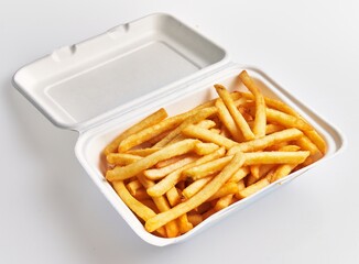 A styrofoam container filled with golden french fries isolated on a white background.