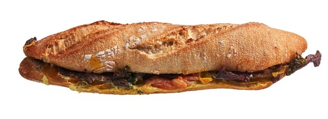 Overhead view of a freshly baked ciabatta sandwich with vegetables and meat on a white background.