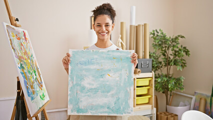 Confident smiling young hispanic woman shows her beautiful art; a passionate artist effortlessly...
