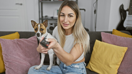 Blonde woman holding dog sitting sofa indoors home