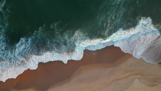 Powerful ocean wave over sand beach. Aerial top down view of sea surf on the beach