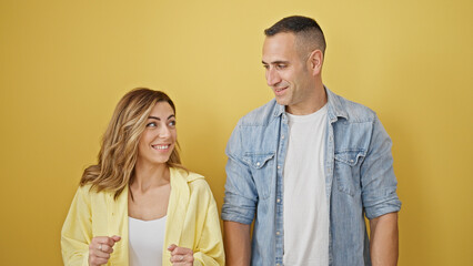 Man and woman couple smiling confident standing together over isolated yellow background