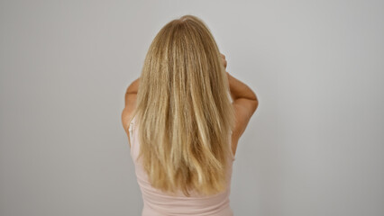 Blonde woman from behind against a white background, showcasing her long hair and pink top.