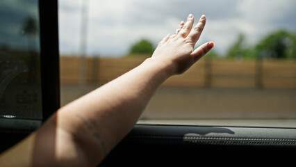 Young beautiful hispanic woman with arm out of the car window on the road