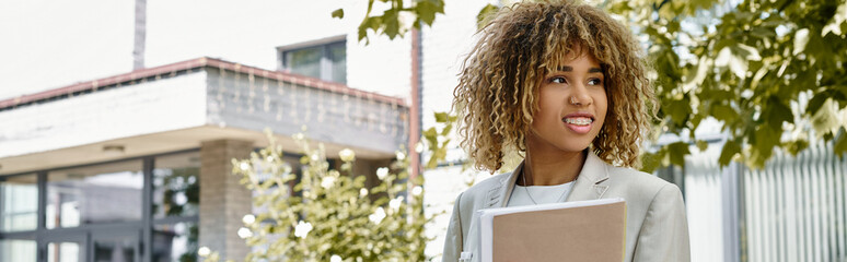 Cheerful african american entrepreneur in braces standing with folder near the office, banner