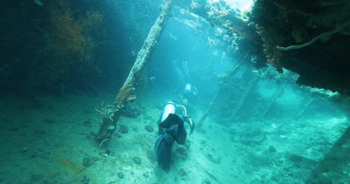 A group of divers diving towards a sunken ship in the Philippine Sea. Exploring Ship Wreck. The ship was Japanese, sunk during WWII. Divers descend into a cloud of bubbles. Summer vacation shot