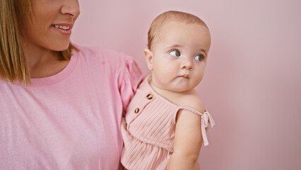 Confident mother enjoying happiness, smiling and holding baby in arms over isolated pink background, celebrating joyful family lifestyle together