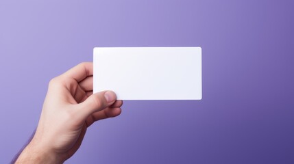 Fototapeta premium Human hand holding a blank sheet of white paper or card isolated on purple background.