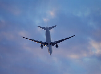 Large airliner with passengers on purple sky is landing at airport of bright sunset on sunny summer day. Go Everywhere.