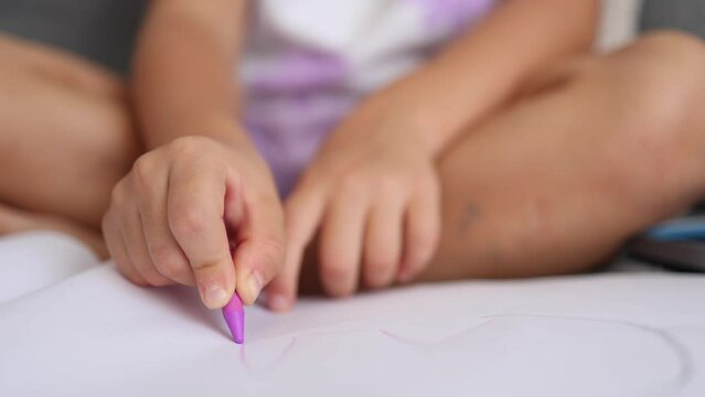 Close-up of little girl's hand with pencil. Five year old girl drawing at home after kindergarten. Magenta color