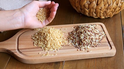 Handful of rice scattered on rustic wooden board, gently poured from palm atop. Witness mesmerizing...