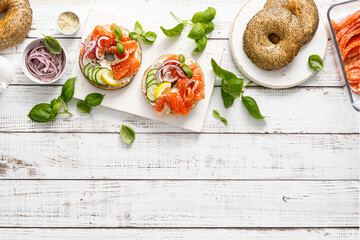Salmon sandwiches with bagel, salted fish, fresh cucmber, onion and basil on white background, top...
