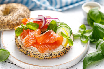 Salmon sandwiches with bagel, salted fish, fresh cucmber, onion and basil on white background. Healthy breakfast with salmon toasts