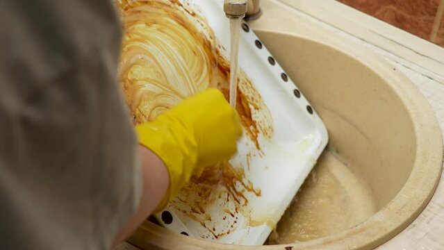 Hands washing the baking tray with a sponge close up