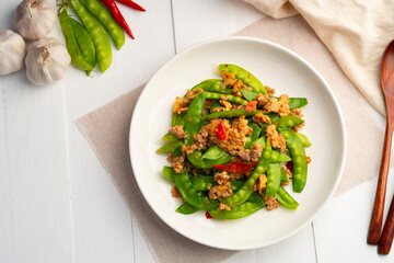 Stir fried snow peas with minced pork in white plate.Thai style food.Top view - obrazy, fototapety, plakaty