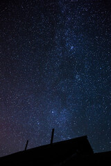 Starry sky with bright stars outside the city in the mountains, no one is there. Silhouette of a...