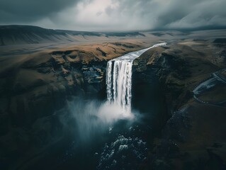 A stunning drone-captured, long-exposure photo of an Icelandic waterfall, enveloped in moody, cinematic clouds with rich black and brown tones.