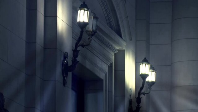 Antique Wall Lights Illuminate the Front Door of An Old Stone Building at Night.