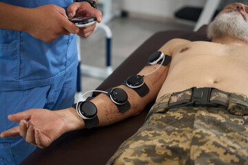 Doctor physiotherapist performs a physiotherapeutic procedure on a military man