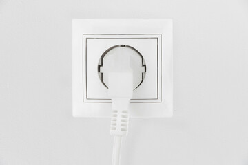 Power electric sockets on a white wall. electric cord plugged into a white electricity rosette on white background. outlet on the white wall