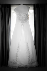 wedding dress on hanger centered in window 