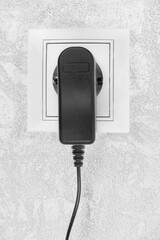 Power electric sockets on a white wall. electric cord plugged into a white electricity rosette on...