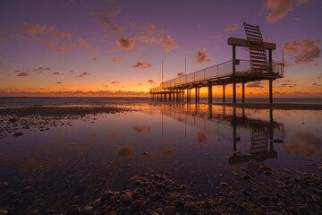 Fototapeta na wymiar Alanya, Antalya, Türkiye, Turkey, Panoramic view of the Mediterranean Sea, low tide, wooden pier reflected in the water, at sunset with a blue and orange sky and clouds, at evening 
