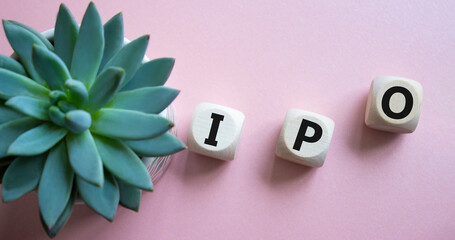 IPO- Initial Public Offering symbol. Concept word IPO on wooden cubes. Beautiful pink background...