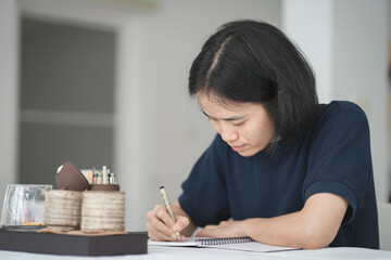 Close up and selective focus hand writing or drawing down on her notebook, work space concept.