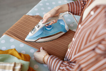 Top view closeup of young woman ironing clothes on ironing board on laundry day copy space