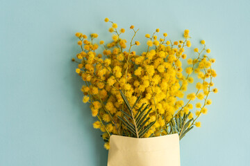 Overhead view of a bunch of yellow mimosa flowers in an envelope on a table