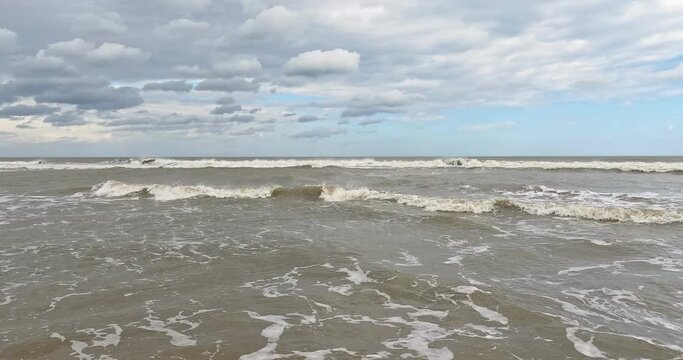 Atlantic seashore with ocean waves, blue sky and rain clouds.  No sandy beach, shot from position standing in the water.