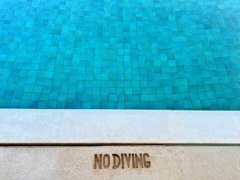 Overhead view of a No Diving sign at the edge of a swimming pool