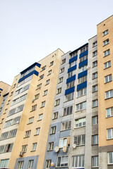 Fototapeta na wymiar Windows of multi-storey tall building against background of sky