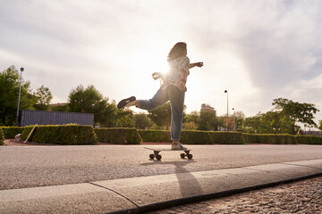 woman riding skateboard in concept hurry. breaking the rules. Active young woman riding skateboard in city at sunset with sun shining in background.