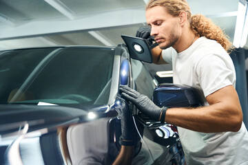 Fototapeta na wymiar Man conducts check inspection of car using powerful lamp