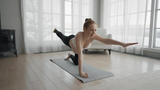 Pregnant woman doing pilates at home. Pregnant female doing yoga practice stretching with online lesson video trainer at home. Mother and child health relax and wellness healthy practices concept.