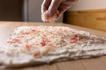 Crab sticks are added to the unfolded pita bread. Preparation of pita bread roll.