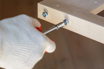 Screwing the screws with a screwdriver. Assembling wooden furniture. Close-up.