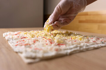 Crab sticks and a boiled egg are added to the unfolded pita bread. Preparation of pita bread roll.
