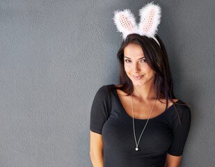 Bunny ears, space or portrait of woman with fashion isolated on wall or grey background with style. Happy model, confident lady or casual female person in studio with smile, easter costume or mock up