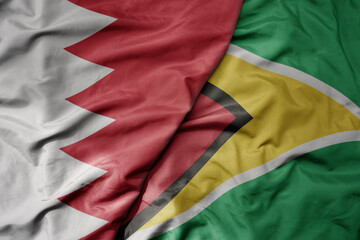 big waving national colorful flag of guyana and national flag of bahrain.
