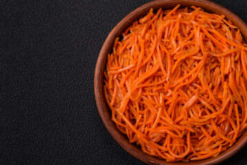 Tasty spicy Korean carrot with spices and herbs on a dark concrete background