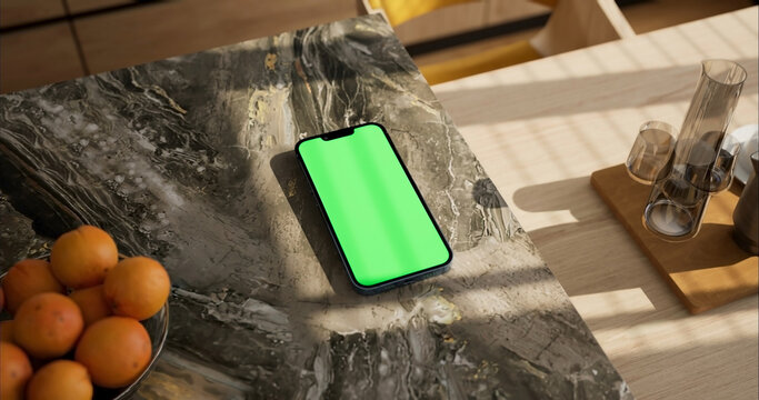 Smartphone place on kitchen table, Green screen telephone, Close up display mobile phone with mock up, Chroma key monitor