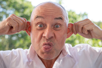 happy senior joking around, making funny faces, caucasian man 60-65 years old smiling, close-up...