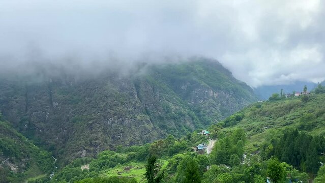 Storm clouds over mountains of Jang town deep in the  jang valley in tawang district of arunachal pradesh and surrounded by high mountains on a bright morning rainy day in arunachal pradesh in India.