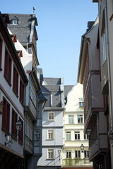 Obraz premium Neu erbaute Häuserzeile im historischen Stil für Touristen mit Gastronomie, Boutiquen und Geschäften vor blauem Himmel im Sonnenschein in der neuen Altstadt am Römerberg in Frankfurt am Main in Hessen