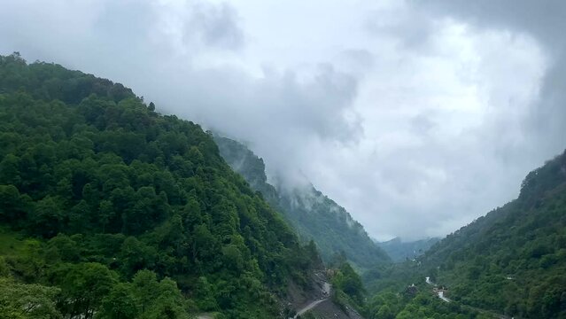 Storm clouds over mountains of Jang town deep in the  jang valley in tawang district of arunachal pradesh and surrounded by high mountains on a bright morning rainy day in arunachal pradesh in India.