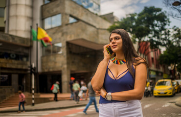 mujer latina en la calle de la ciudad llamando por teléfono 